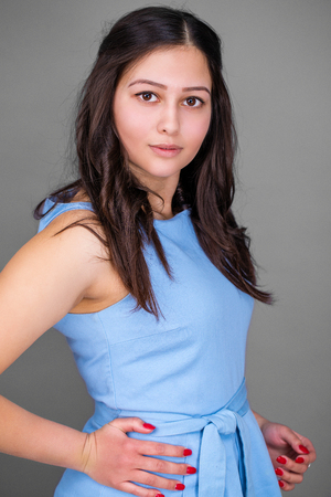 Young pretty American girl in a blue dress, isolated on a gray backgroundの写真素材