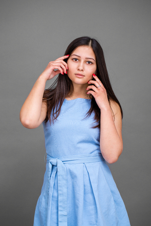 Young pretty American girl in a blue dress, isolated on a gray backgroundの写真素材
