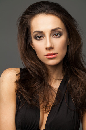 Beautiful brunette model face close up portrait studio isolated on dark gray backgroundの写真素材