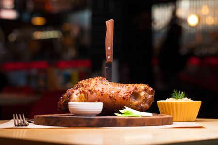 Restaurant dish - a large baked pork knuckle on a wooden trayの写真素材
