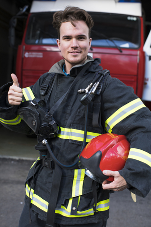Close-up portrait of a young fireman on the background of a fire truckの写真素材