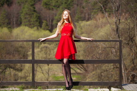 Young beautiful blonde woman in red sexy dress, spring park outdoorsの写真素材