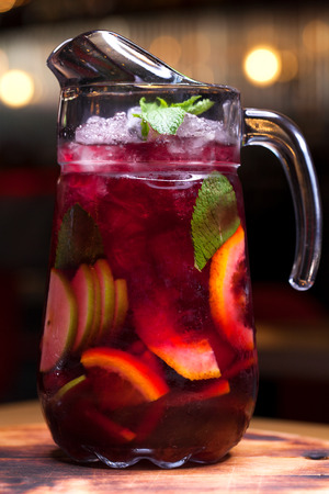 Homemade red wine sangria with orange, apple, strawberry and ice in glass and pitcherの写真素材