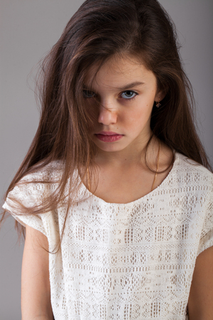 Portrait of a charming brunette little girl, isolated on gray backgroundの写真素材