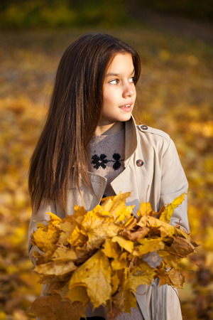 Happy young little girl in beige coat in autumn parkの写真素材