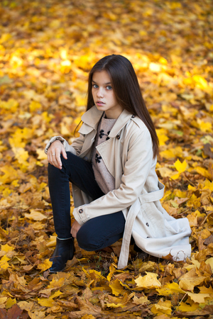 Happy young little girl in beige coat in autumn parkの写真素材