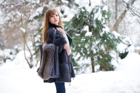 Full length portrait of young beautiful elegant brunette woman wearing fur coat. Fashionable girl walking at the street at winter.の写真素材