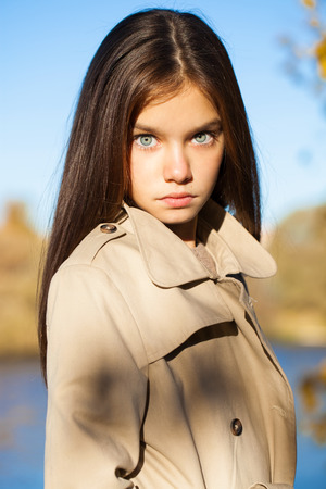 Portrait of a beautiful young brunette little girl, autumn park outdoorsの写真素材
