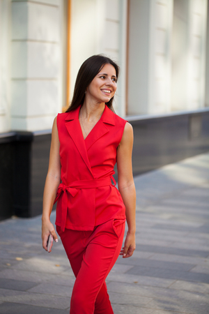Portrait in full growth of a beautiful young woman in red suit, street summer outdoorsの写真素材