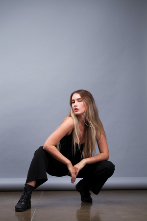 Happy Beautiful blonde woman in black dress, studio isolated on gray backgroundの写真素材