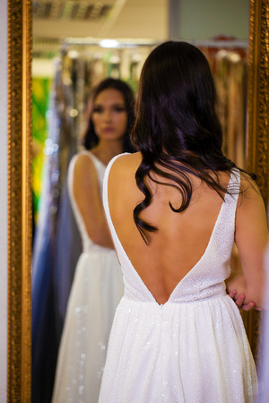 Young woman trying on new dress in showroom. Fashion and choice concept, brunette model in black sexy dressの写真素材
