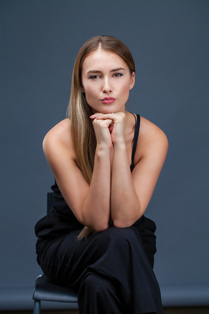 Happy Beautiful blonde woman in black dress, studio isolated on gray backgroundの写真素材
