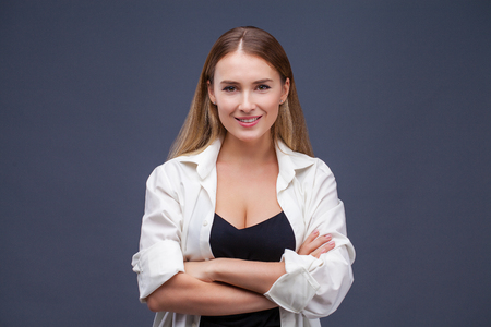 Happy blonde model. Portrait of beautiful young woman in white shirt, isolated on gray backgroundの写真素材