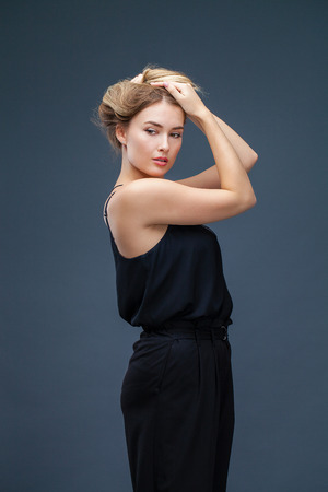 Happy Beautiful blonde woman in black dress, studio isolated on gray backgroundの写真素材