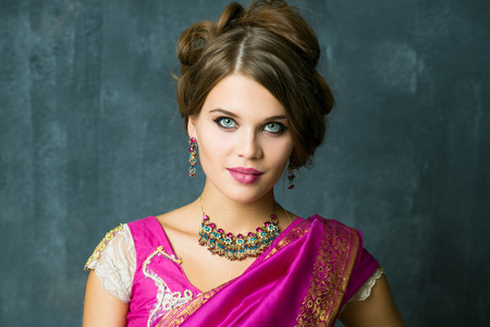 Beautiful fashion brunette woman portrait with oriental accessories earrings. Arabic girl with beauty jewels. European model with perfect make-upの写真素材