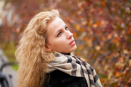 Russian girl. Portrait of beautiful young blonde woman in neckerchief, autumn park outdoorsの写真素材