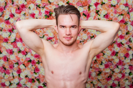Portrait of a young sexy guy on the background of floral studio wallの写真素材