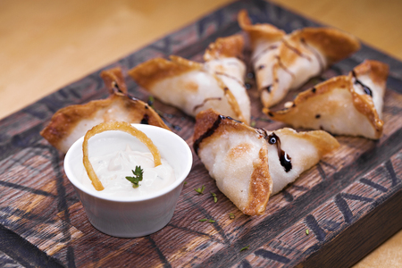 Restaurant dish. Fried dumplings with spicy sauce on a wooden tray