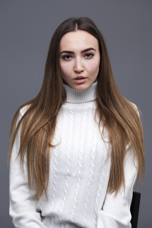 Close up portrait young brunette woman in white sweater, isolated on gray backgroundの写真素材