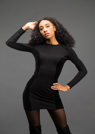Young beautiful african american woman posing in elegant black dress, Studio shot.の写真素材
