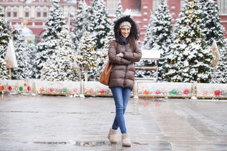 Portrait of a young brunette woman in down jacket on a red square in the center of Moscowの写真素材