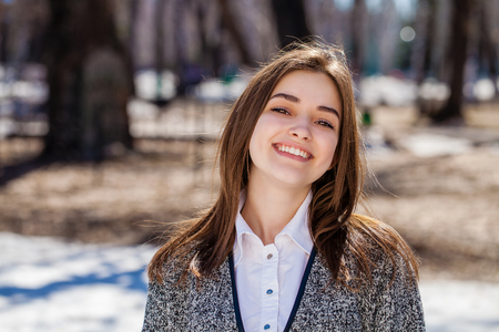 Close up. Young beautiful brunette girl in gray coat posing on spring parkの写真素材