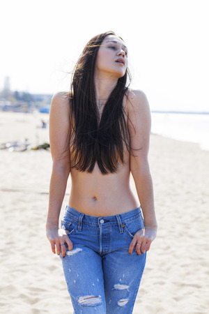 Sexy brunette young woman posing flirty topless at river, summer outdoorの写真素材