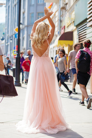Portrait in full growth, young beautiful brunette woman in pink dress walking on the street, summer outdoorsの写真素材