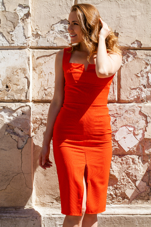 Portrait close up of young beautiful happy blonde woman in red dress, summer street outdoorsの写真素材