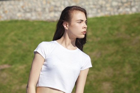 Close up hair style. Young beautiful teenager girl posing against summer park, bright sunny weatherの写真素材