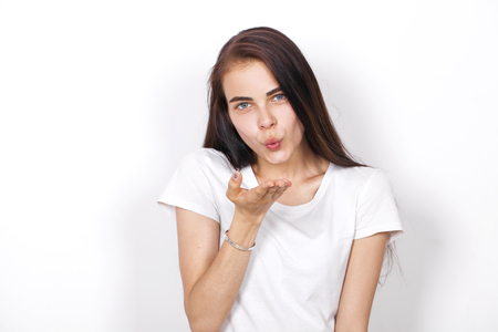 Blow kiss, young caucasian female brunette model, isolated on white backgroundの写真素材