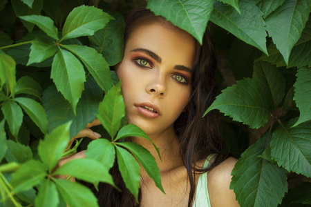 Close up portrait of a young beautiful girl in green ivy foliageの写真素材