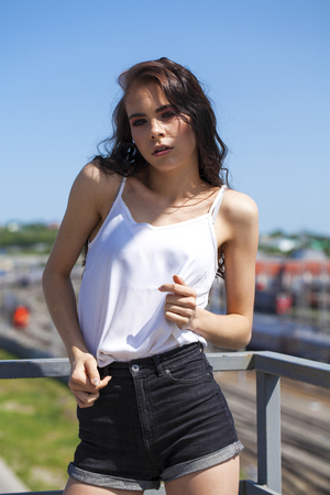 Portrait of a pretty young brunette model in white summer blouse and jeans, summer street outdoorsの写真素材