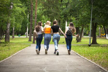 Full body happy women in blue jeans walking in summer park, outdoorsの写真素材