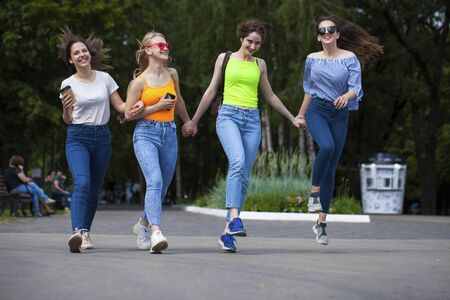 Full body happy women in blue jeans walking in summer park, outdoorsの写真素材