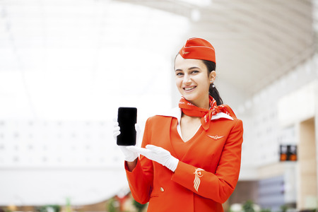 RUSSIA, MOSCOW: 28 JUNE 2019. Beautiful stewardess dressed in official red uniform of Aeroflot Airlines on airport. Young woman with mobile phoneのeditorial素材