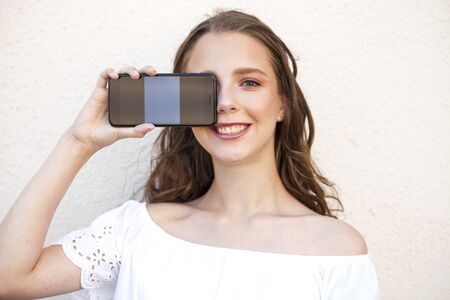 Young beautiful brunette woman showing your smartphone screen