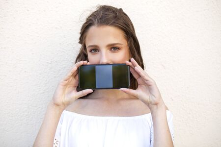 Young beautiful brunette woman showing your smartphone screen
