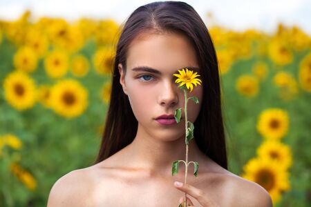 Close up portrait of a young beautiful girl in a field of sunflowersの写真素材