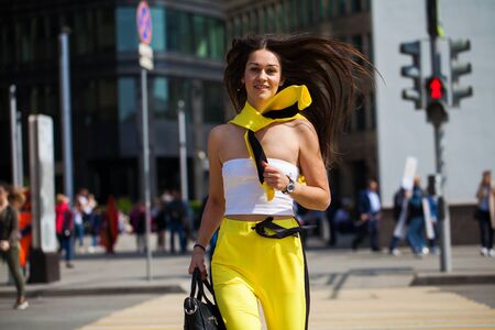 Full length portrait of a young beautiful brunette woman in yellow jumpsuit posing on the streetの写真素材