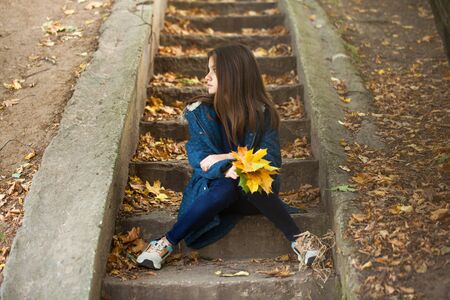 Pretty stylish brunette girl posing in autumn park backgroundの写真素材