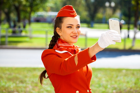 RUSSIA, SAMARA: 08 AUGUST 2019. Beautiful stewardess dressed in official red uniform of Aeroflot Airlines, Summer street outdoorsのeditorial素材