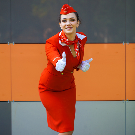 RUSSIA, SAMARA: 08 AUGUST 2019. Beautiful stewardess dressed in official red uniform of Aeroflot Airlines, Summer street outdoorsのeditorial素材