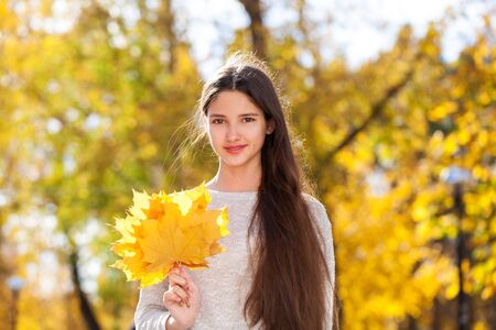 Happy brunette girl posing in autumn park background
