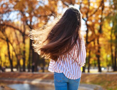 Back view hair brunette girl posing in autumn park backgroundの写真素材