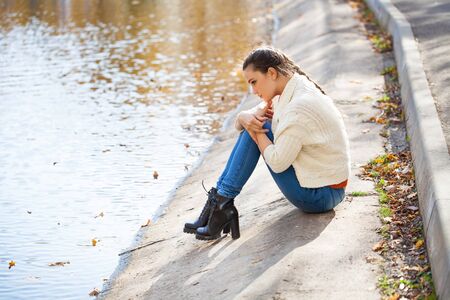 Full body portrait of a young beautiful woman in blue jeans posing in autumn park