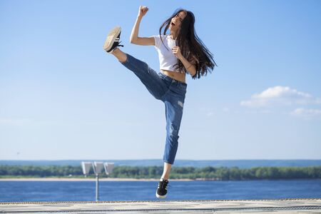 Full body girl in a jump. Young beautiful brunette woman posing against blue sky bright sunny weatherの写真素材