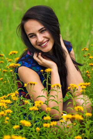Portrait close up of young beautiful brunette woman in summer green grassの写真素材