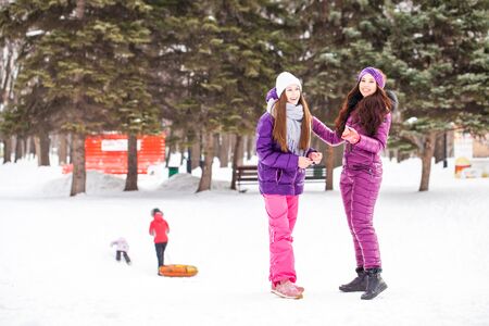 Full-length portrait of a young beautiful brunette girl in a ski suit posing in winter parkの写真素材