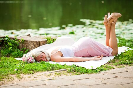 Full-length portrait of a young woman resting near a pond in a summer parkの写真素材